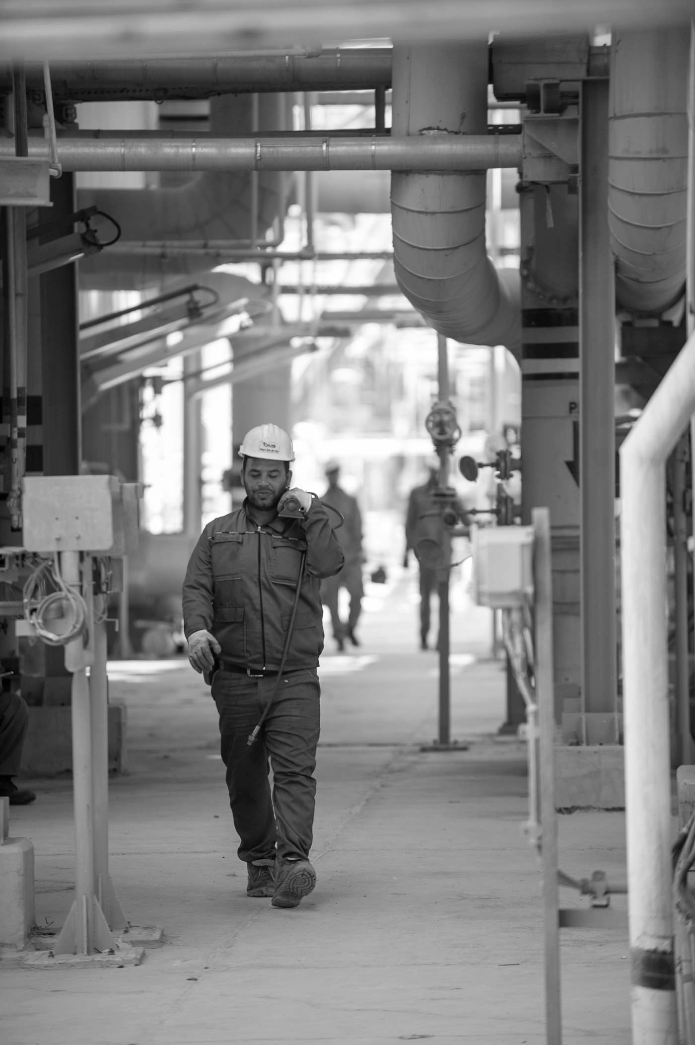 Gerente con casco blanco recorriendo una planta industrial